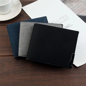 Short canvas wallets for men in navy, grey, and black on a wooden background with accessories