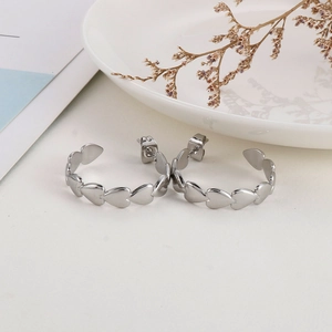 Macro detail of silver-finish heart-linked hoop earrings with butterfly backing