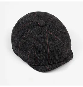Detailed top view of newsboy cap showing dark grey herringbone and orange windowpane check