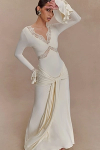 Detail of white V-neck dress with intricate lace trim and silky pleated skirt texture