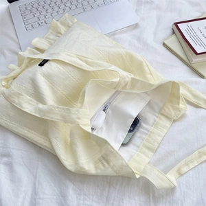 Detail view of cream tote bag interior showing inner pocket for phone and earbuds