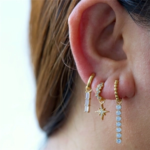 Gros plan de boucles d'oreilles créoles dorées avec pendentifs en étoile et barre en zircon