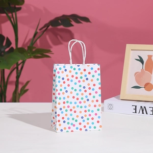 Close-up of a white paper gift bag with colorful polka dots and twisted paper handles