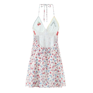 Detail of white halter dress featuring cherry embroidery and scalloped lace neckline