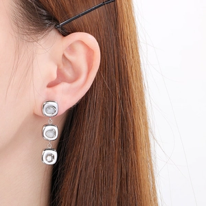 Detail of silver long square drop earrings featuring cat-eye stones and crystal accents