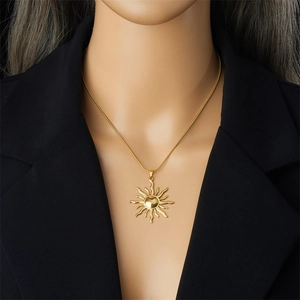 Gold sun totem pendant necklace with fine snake chain displayed on a black background