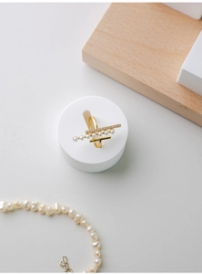 Macro view of gold pearl ring with cubic zirconia on a white plaster display stand