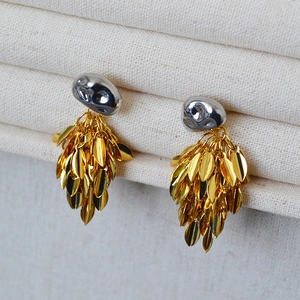 Macro detail of mixed-metal leaf tassel earrings with hammered pebble studs