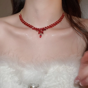 Close-up of elegant gold Y-necklace with red gemstones worn on model's neckline