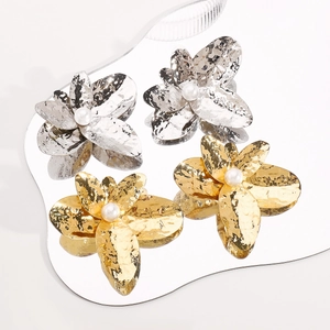 Macro shot of metallic hammer-textured floral earrings with faux pearl center and mirrors