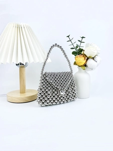 Chic silver beaded handbag with spherical pearls on a minimalist studio background