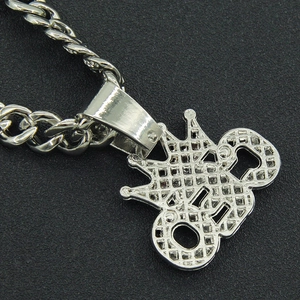 Macro shot of silver hip hop CEO crown pendant with full diamonds and Cuban chain