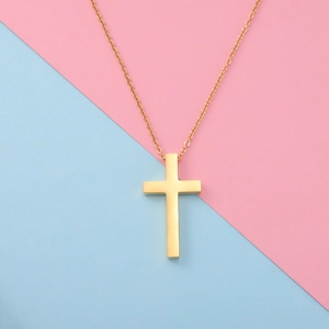 Detail of a golden cross pendant necklace on a creative pastel pink and blue background