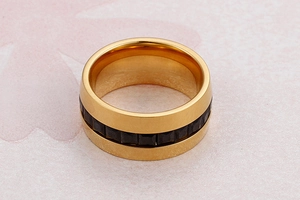 Macro shot of gold-plated wide band ring with channel-set black square zirconias