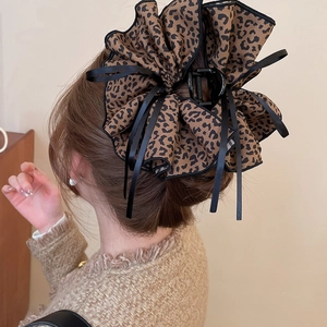 Detail of leopard print bow hair claw with black ribbons on a knitted sweater background