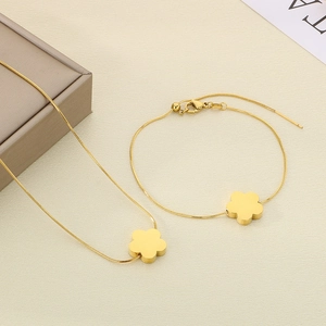 Detail of gold clover necklace and snake chain bracelet set in luxury gift box
