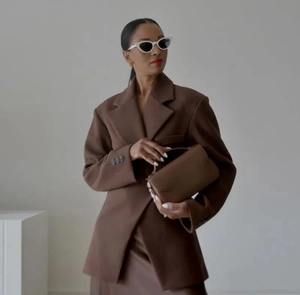 Detail of dark brown lapel blazer paired with high waist skirt and chic sunglasses