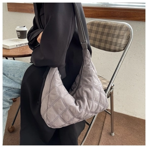 Lifestyle view of a light purple quilted shoulder bag with diamond stitching on a model