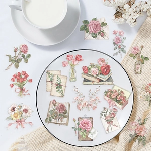 Flat lay of vintage floral stickers with roses and letters on a beige tablecloth