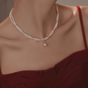 Close-up of double layer pearl necklace featuring a large oval pearl and gold clasp