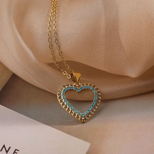 Gold plated heart pendant necklace with blue stones and hollow woven texture on silk