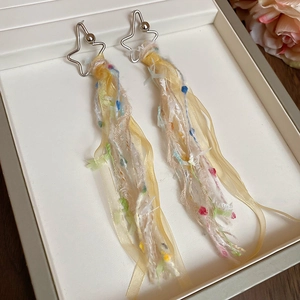 Détail des boucles d'oreilles à pampilles étoiles avec organza coloré et dentelle sur présentoir