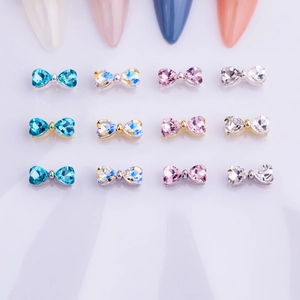 Macro detail of colorful bow-tie nail charms with heart crystals on mixed metal bases