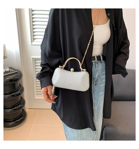 Silver glitter evening clutch with gold metal handle and chain shown as a shoulder bag