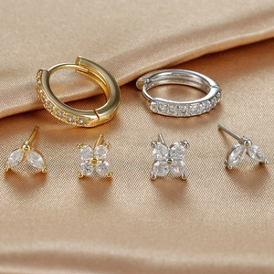 Macro shot of gold and silver S925 earrings set with sparkling cubic zirconia on silk cloth