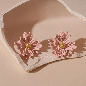 Macro detail of 3D pink flower stud earrings with golden pistil on artistic tray