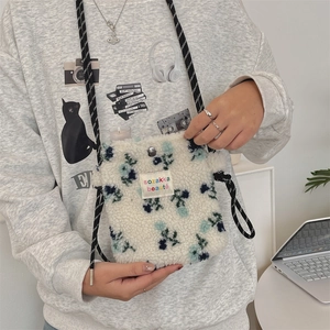 Detail of floral sherpa crossbody bag featuring woven texture and twisted rope strap