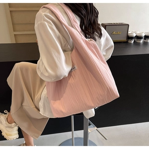 Schultertasche in rosa Faltenoptik mit weißem Markenlabel in minimalistischem Café-Ambiente