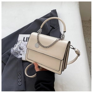 Detail of cream white PU leather handbag with gold chain ornament and round logo tag