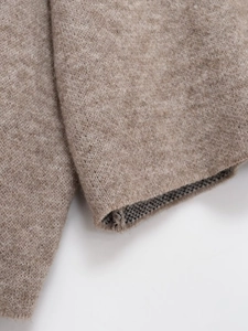 Detailed close-up of light brown knitted sweater cuff showing fine ribbed texture and quality