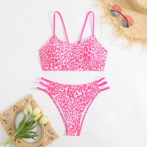 Flat lay of pink leopard print bikini set with summer accessories on white background