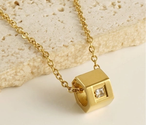 Macro detail of golden hexagonal prism pendant with a square white zircon on stone