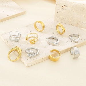 Detail showing assorted gold and silver stainless steel safety pin and wave rings on stone