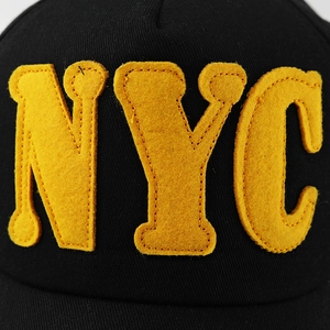 Close-up of yellow felt NYC letter embroidery on a black washed cotton baseball cap