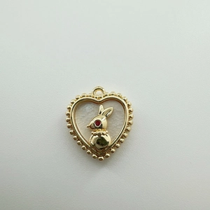 Detailed macro view of 18K gold heart pendant with white shell inlay and golden bunny