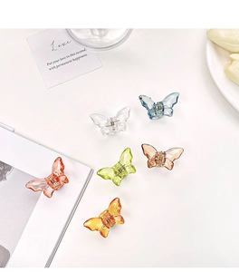Detailed overhead shot showing six colorful translucent butterfly hair claw clips on a desk