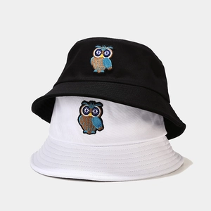 Stack of black and white cotton bucket hats featuring detailed owl embroidery