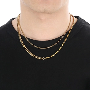 Detail of gold-layered necklace featuring a cuban link chain and bar segments on a model