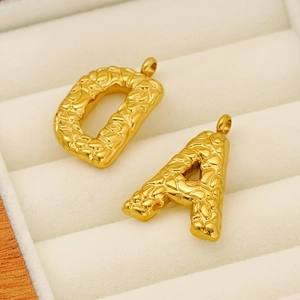 Golden textured initial letter D and A necklaces on beige velvet jewelry display case