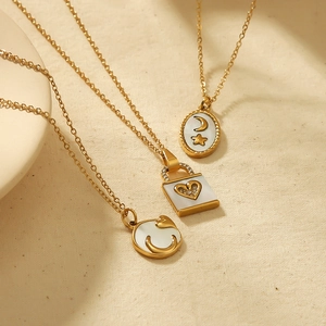 18k gold plated stainless steel necklaces with shell heart and moon charms on beige linen