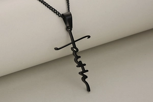 Close-up of a black stainless steel cross pendant featuring the Faith word design