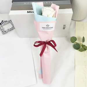 Close-up of a single white soap rose bouquet wrapped in pastel paper with ribbon
