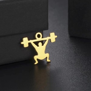 Macro view of a golden stainless steel weightlifter silhouette pendant on black surface