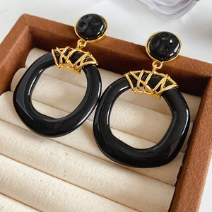Détail de boucles d'oreilles géométriques vintage en résine noire dans leur boîte