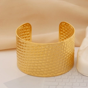 Close-up of wide gold-plated stainless steel cuff bracelet with woven textured finish