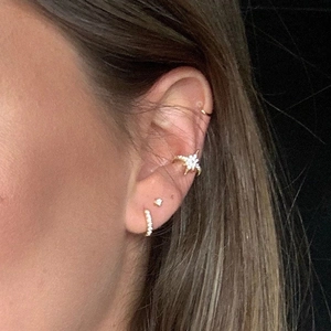 Detailed view of model wearing gold star ear cuffs and zircon stud earring set
